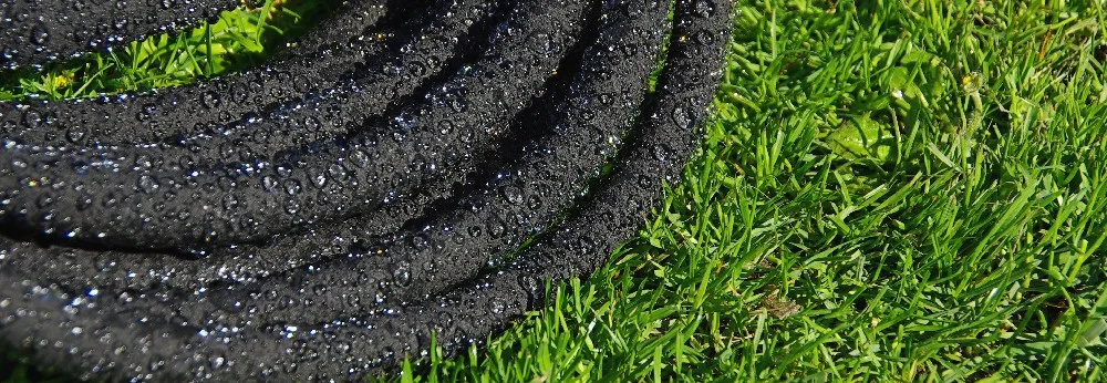 Schwarzer Gartenschlauch auf Rasen